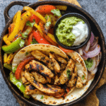 Oven Baked Sheet Pan Chicken Fajitas served with warm tortillas and various toppings.