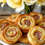 A close-up of a Cheesy French Pinwheel, showing the flaky layers and melted cheese.