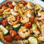 Ingredients for Shrimp Tomato Zucchini Pasta, including shrimp, zucchini, tomatoes, and pasta.