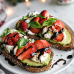 Arranging sliced strawberries and torn burrata over mashed avocado on toast for Strawberry Avocado Toast.