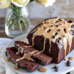 The whole glazed Chocolate Baileys Bread loaf on a cutting board, partially sliced, perhaps next to a cup of coffee.