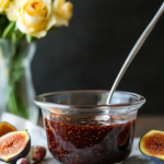 A fresh green salad being drizzled with Fig Balsamic Vinaigrette.