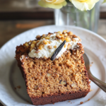 The whole Carrot Cake Loaf on a cutting board, partially sliced, with a bowl of the ricotta topping nearby.