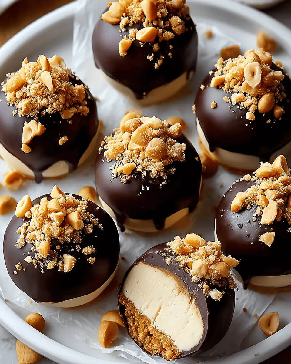 A white platter of chocolate-dipped peanut butter cheesecake bites, generously sprinkled with crushed peanuts.