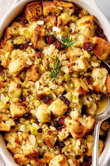 A scoop of sourdough apple stuffing on a Thanksgiving plate, next to sliced turkey and gravy.