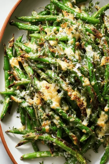 7 A large baking sheet of green beans roasted with garlic, topped with melted and golden-brown Parmesan and mozzarella cheese.