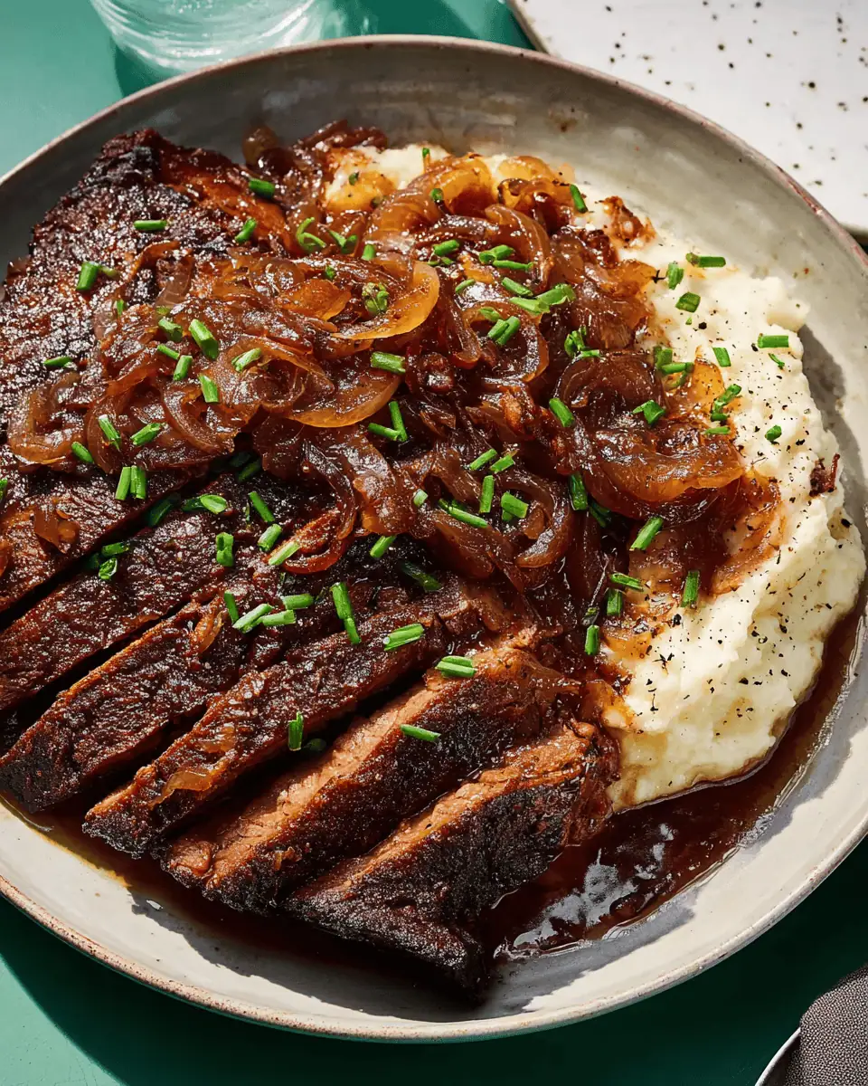 Tender Onion-Braised Brisket with Stout Beer Gravy 3 Sliced braised beef brisket covered in rich onion gravy served on a platter with herbs.