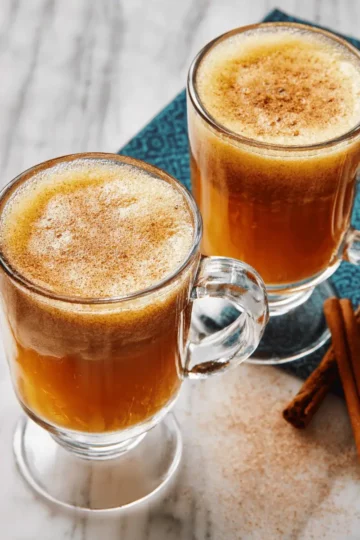 Hot Buttered Rum - The Ultimate Winter Warmer 9 A small saucepan on a stove filled with warm apple cider and spices.