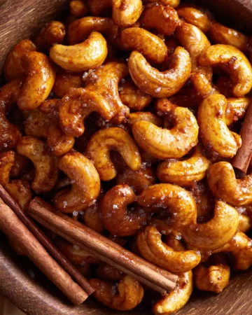 Delicious honey roasted cashews fresh out of the oven, perfect snack for parties, easy recipe for crunchy treats, sweet and salty flavors.